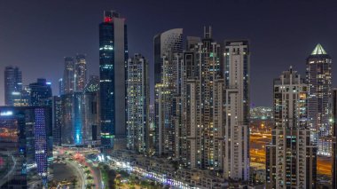 Bay Bulvarı 'nda Business Bay hava sahasında modern kuleler var. Tüm gece, Dubai, BAE' de. Parlayan pencereleri ve ışıkları sönen gökdelenler