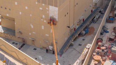 İnşaat işçileri vinç aracının içinde hava zaman tüneli inşa etme cephesini onarmak ve onarmak için çalışıyorlar. Duvarı yeni bir renge boyuyorum.