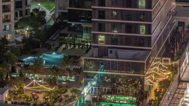 Açık havada yüzme havuzu olan rahat bir restoran ve barın hava manzarası. Dubai 'deki iş yerlerinde masalarda oturan insanlar..