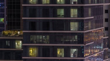 Gece karanlığa bürünmüş gökdelen perdeleriyle kaplı bir daire penceresi şehrin ışıklarının yansıması havadan zaman ayarlı. Aydınlatılmış kuleler