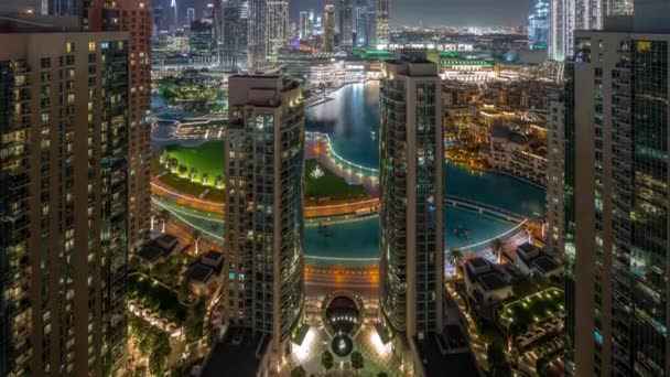 Dubai cantando fuentes con zona de paseo alrededor de la vista aérea nocturna entre rascacielos timelapse. — Vídeos de Stock
