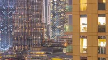 Dünya saatinde Dubai 'de, Birleşik Arap Emirlikleri' nde gece balkonlarında restoranlarla alışveriş merkezleri açılır. Arka planında en yüksek gökdelen olan gökyüzü manzarası. Işıklar yanıyor.