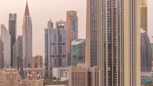 アラブ首長国連邦ドバイのシェイク ザイド ロードとDifc地区航空昼から夜への遷移時間経過の周りの高層ビルの行 ガラス面を持つ国際金融センターの超高層ビル — ストック写真
