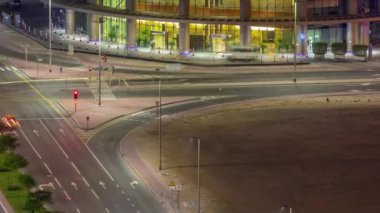 Dubai iş sahası girişi ofis gökdeleni ve yol kesişimindeki trafik gece saat kavşağı.