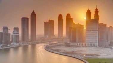 Dubai İş Körfezi 'ndeki gökdelenlerin günbatımında su kanallarının zaman ayarlı görüntüsü.
