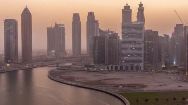 Dubai İş Koyu 'ndaki gökdelenlerin şehir manzarası. Su kanalı havası günden geceye zaman geçiyor.