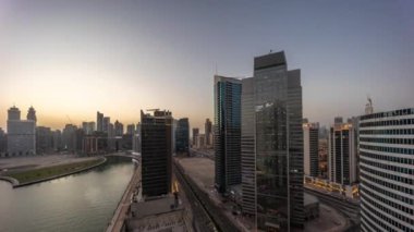 Dubai İş Koyu 'ndaki gökdelenlerin şehir manzarası. Su kanalı havası günden geceye zaman geçiyor.