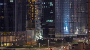 Dubai iş sahası bölgesi ofis gökdelenleri ve kavşağındaki yol kavşağındaki hava trafiği gece saat dilimi. İHA 'nın kavşağında hareket eden arabaların aydınlatma kulelerinde yansımalar