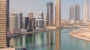 Şehir manzarası gökdelenleri ve Dubai Business Bay 'in su kanalları zaman ayarlı şantiyesi. Kuleleri ve limanı olan modern gökyüzü. Uluslararası bir iş merkezi.