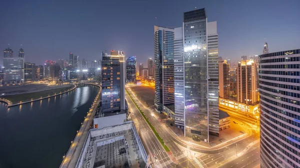迪拜商业湾摩天大楼的城市景观与水渠空中通宵的过渡时间过去了 日出前拥有照明塔和公路交通的现代天际线 — 图库照片