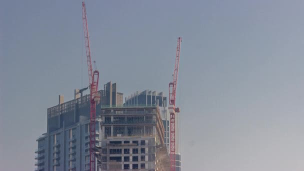 Dois guindastes trabalhando em obras de construção de novos arranha-céus timelapse — Vídeo de Stock