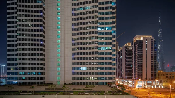 ビジネスベイ地区の夜のタイムラプスの交差点で忙しい交通とドバイのダウンタウンオフィス高層ビルへの空中パノラマビュー 屋上の照明付きスイミングプール — ストック写真