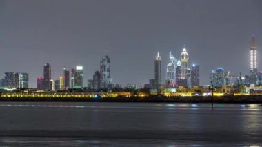 Modern Dubai şehir manzarası timelapse su yüzeyi üzerinde ışıklandırılmış gökdelenler ile gece