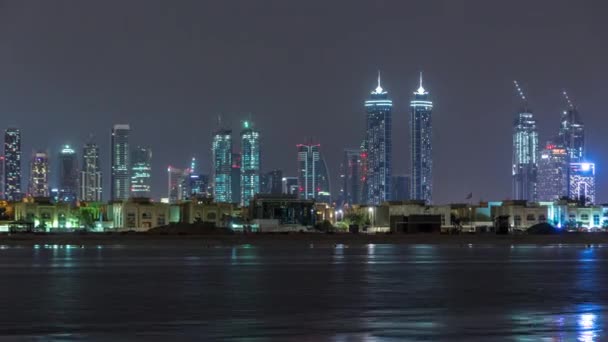 Moderne Skyline Dubais bei Nacht mit beleuchteten Wolkenkratzern über der Wasseroberfläche — Stockvideo