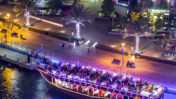 Touristisches Holzschiff in der Bucht des Yachthafens Dubai nachts im Zeitraffer beleuchtet — Stockvideo