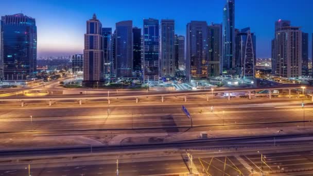 Flygfoto över Jumeirah lakes towers skyskrapor natt till dag timelapse med trafik på sheikh zayed road. — Stockvideo