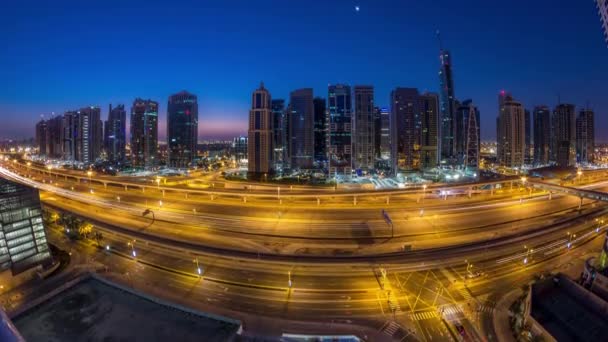 Vista aérea de las torres de los lagos de Jumeirah rascacielos noche a día timelapse con el tráfico en la carretera sheikh zayed . — Vídeos de Stock