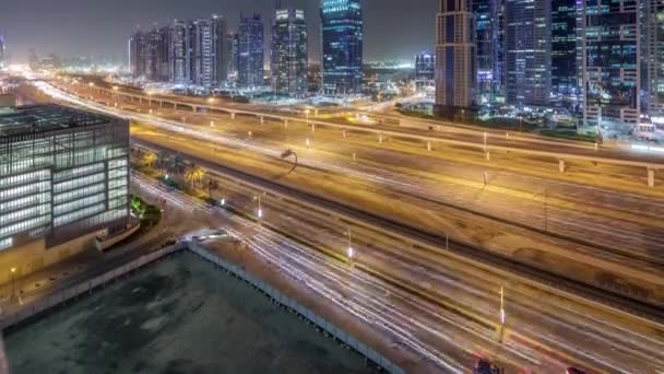 Flygfoto över Jumeirah lakes towers skyskrapor natt timelapse med trafik på sheikh zayed road. — Stockvideo
