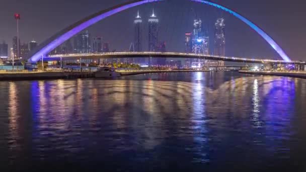 Futuristinen jalankulkusilta Dubain vesikanavan yllä valaistu yöllä timelapse, Arabiemiirikunnat . — kuvapankkivideo