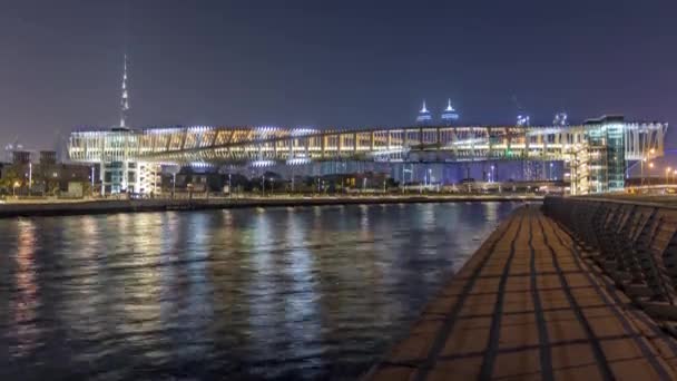 Pont piétonnier futuriste au-dessus du canal d'eau de Dubaï illuminé la nuit timelapse, EAU . — Video