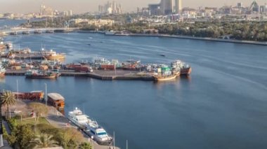Dubai creek manzara timelapse tekneler ve gemi limanda ve gün batımı sırasında arka planda modern binalar