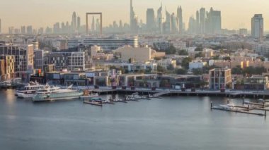 Dubai deresi zaman çizelgesi, deniz manzarası ve günbatımında arka planda modern binalar.