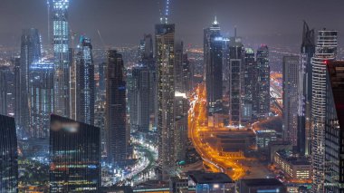 Şehir merkezinin ufuk çizgisi, modern mimari biçimle gece zamanının üstünde. Dubai iş sahasının havadan panoramik görüntüsü aydınlatma kuleleri.