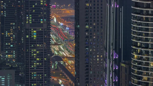 迪拜市中心的高速公路和摩天大楼之间的立交桥 窗户明亮 夜间空中穿行 地铁站附近塔楼窗户明亮 上头交通繁忙 — 图库照片