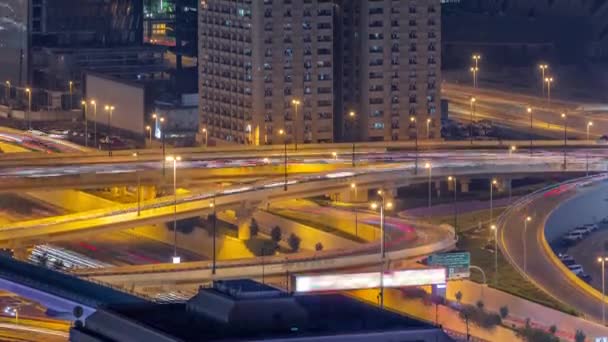 Duże skrzyżowanie autostrady i kanał wodny Dubaju z mostem dla pieszych nad nim powietrza nocy timelapse. — Wideo stockowe