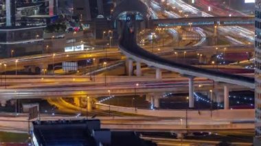 Meşgul Şeyh Zayed Yolu kavşağı hava gece zaman çizelgesi, metro yolu ve Dubai civarındaki modern gökdelenler..
