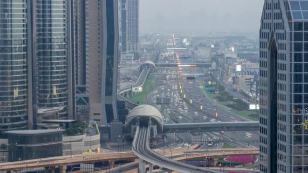 Ocupado Sheikh Zayed carretera aérea día a noche timelapse, metro ferrocarril y rascacielos modernos alrededor en la ciudad de lujo de Dubai. — Vídeo de stock