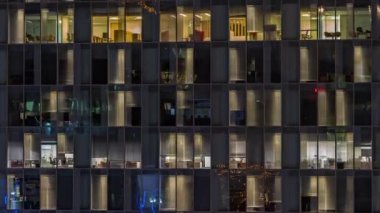 Aydınlatılmış çalışma odaları zaman ayarlı ofis cam pencere cephesinin gece hava görüntüsü.