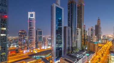 Dubai Uluslararası Finans Bölgesi 'nin hava görüntüsü. Günbegün geçiş zamanı birçok gökdelen var. Metro istasyonu yakınlarındaki bir yolda trafik ve çatısı yüzme havuzlu çok katlı bir otopark. Dubai, BAE.