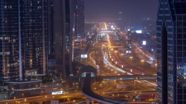 Sheikh Zayed Yolu 'nda gece gündüz yoğun geçiş zamanları, metro rayları ve lüks Dubai şehrindeki modern gökdelenler. Otobanda bir sürü araba var. Birleşik Arap Emirlikleri