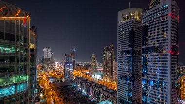 Dubai Uluslararası Finans Bölgesi 'nin birçok gökdelenli gece görüşü. Yol kavşağında trafik ve ofis kulelerinde parlayan pencereler. Dubai, BAE.