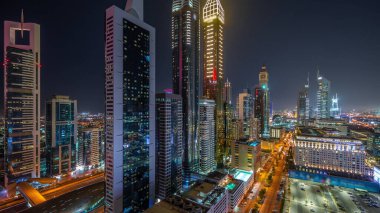 Dubai Uluslararası Finans Bölgesi 'nin panoramik hava manzarası ve birçok gökdelen gece zaman çizelgesi. Meşhur kulelerin yakınındaki yolda trafik vardı. Dubai, BAE.