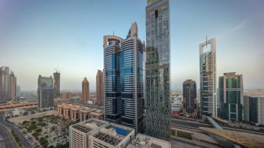 Dubai Uluslararası Finans Bölgesi 'nin panoraması. Gün doğumundan günbatımına kadar birçok gökdelen zaman çizelgesi var. Bütün gün boyunca çok katlı otoparkın yakınındaki bir yolda trafik vardı. Dubai, BAE.