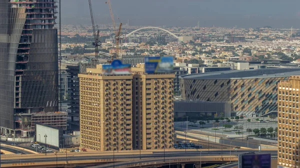 大型公路交叉口和迪拜水渠 背景上有人行天桥 建筑工地上有起重机的空中飞行时间 许多房屋和别墅在交叉口后面 — 图库照片