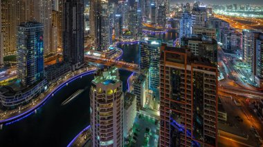 Dubai Marina hava sahasının en uzun bloğundaki çeşitli gökdelenlerin görüntüsü suni kanallı gece zaman ayarlı. Bir sürü kule ve yat. Köprülerde trafik