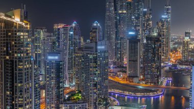 Dubai Marina hava sahasının en uzun bloğundaki çeşitli gökdelenlerin görüntüsü suni kanallı gece zaman ayarlı. Parlayan pencereleri ve yatları olan pek çok kule