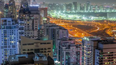 Dubai 'de lüks bir semt ve golf kulübü gece saatleri var. Dubai marina gökdelenleri yakınlarındaki kulelerin ve yol kavşağının havadan görüntüsü