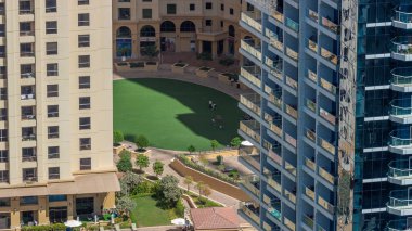 Çatıdaki yüzme havuzu, JBR bölgesinin havuz manzarası. İnsanlar yeşil bir çimenlikte yüzüyor ve dinleniyorlar. Dubai, BAE