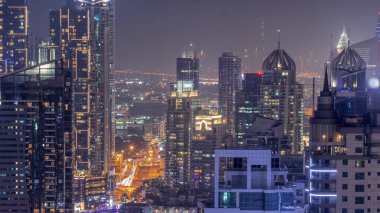 Dubai Marina ve Media City semtleri modern gökdelenler ve ofis binaları tüm gece boyunca antenli. Üstgeçitte trafik ve ışıkların kapandığı kavşak.