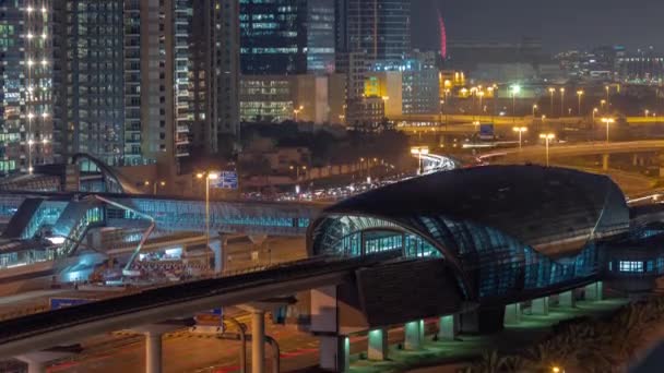 Футуристическое здание станции метро Дубай и роскошные небоскребы позади в Дубай Марина воздушных ночей — стоковое видео