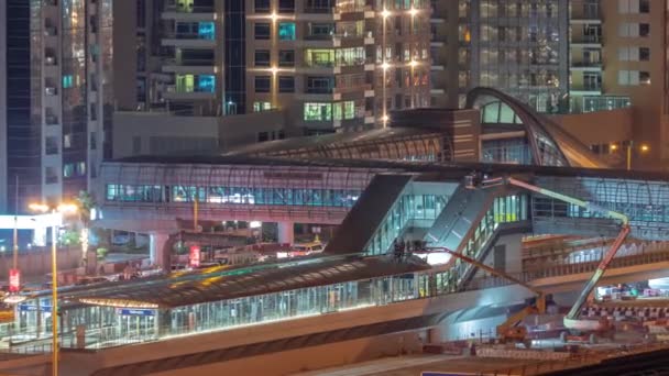 Futuristisk byggnad av Dubai spårvagnstation och lyx skyskrapor bakom i Dubai Marina antenn natt timelapse — Stockvideo
