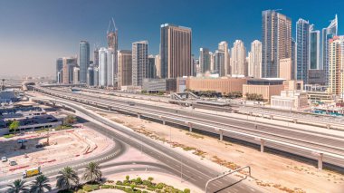 Dubai Marina gökdelenleri ve Şeyh Zayed yolu ile metro demiryolu panoramik zaman çizelgesi. Modern kulelerin yakınındaki bir otoyolda trafik var, Birleşik Arap Emirlikleri