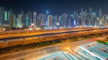 Dubai marinası tüm gece boyunca gökdelenlerin en yüksek binası ve ışıkları kapalı. JLT bölgesinden apartman binalarına, otellere ve otoyola yakın ofis kulelerine hava panoramik görüntüsü.