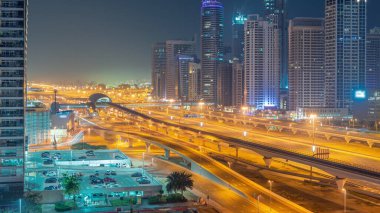 Dubai Marina gökdelenleri ve Şeyh Zayed yolu, gece gündüz metro hava yolu geçiş zamanı. Gündoğumundan önce modern kulelerin yakınındaki bir otoyolda trafik vardı, Birleşik Arap Emirlikleri