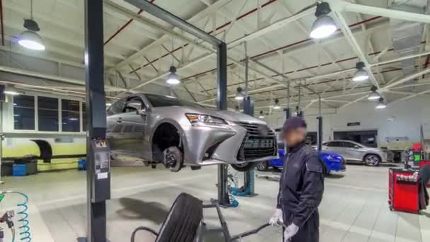 Coche mecánico atornillado y desenroscar la rueda del coche del automóvil levantado en la estación de servicio de reparación timelapse hyperlapse — Vídeo de stock