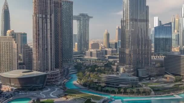 Небоскрёбы, возвышающиеся над центром Дубая по времени, торговый центр и фонтан в окружении современных зданий — стоковое видео